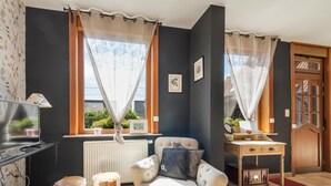Een gezellige woonkamer met een bank, een bijzettafeltje, een radiator en een raam met gordijnen.