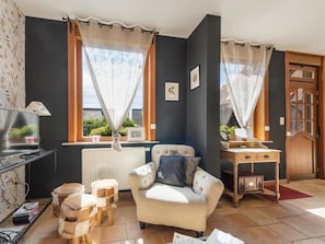 Un salon confortable avec un canapé, une petite table, un radiateur et une fenêtre avec des rideaux.