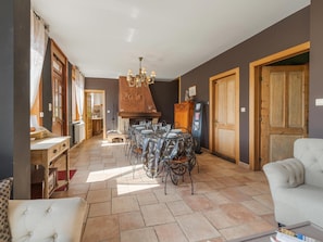 A dining area with a fireplace, a chandelier, and a table set for six.
