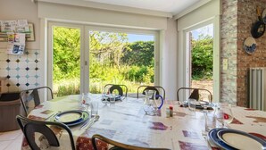 Comedor con una mesa dispuesta para cuatro personas, ventanas amplias y una pared de ladrillo.
