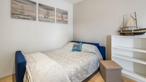 Ein Schlafzimmer mit einem Bett, einem Regal mit einem Modellschiff und drei Bildern an der Wand.