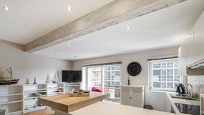 Eine moderne Küche mit weißen Schränken, einer Holzarbeitsplatte, einem großen Fenster und einer Uhr an der Wand.
