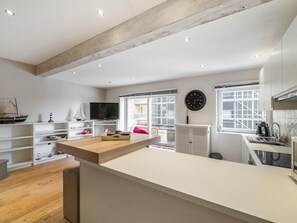 A modern kitchen with white cabinetry, a wooden countertop, a large window, and a clock on the wall. - Studio with a view of the harbor. (Blankenberge)