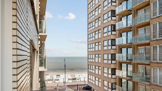 Ein Hochhaus mit mehreren Balkonen, einem Parkplatz und Blick auf das Meer.