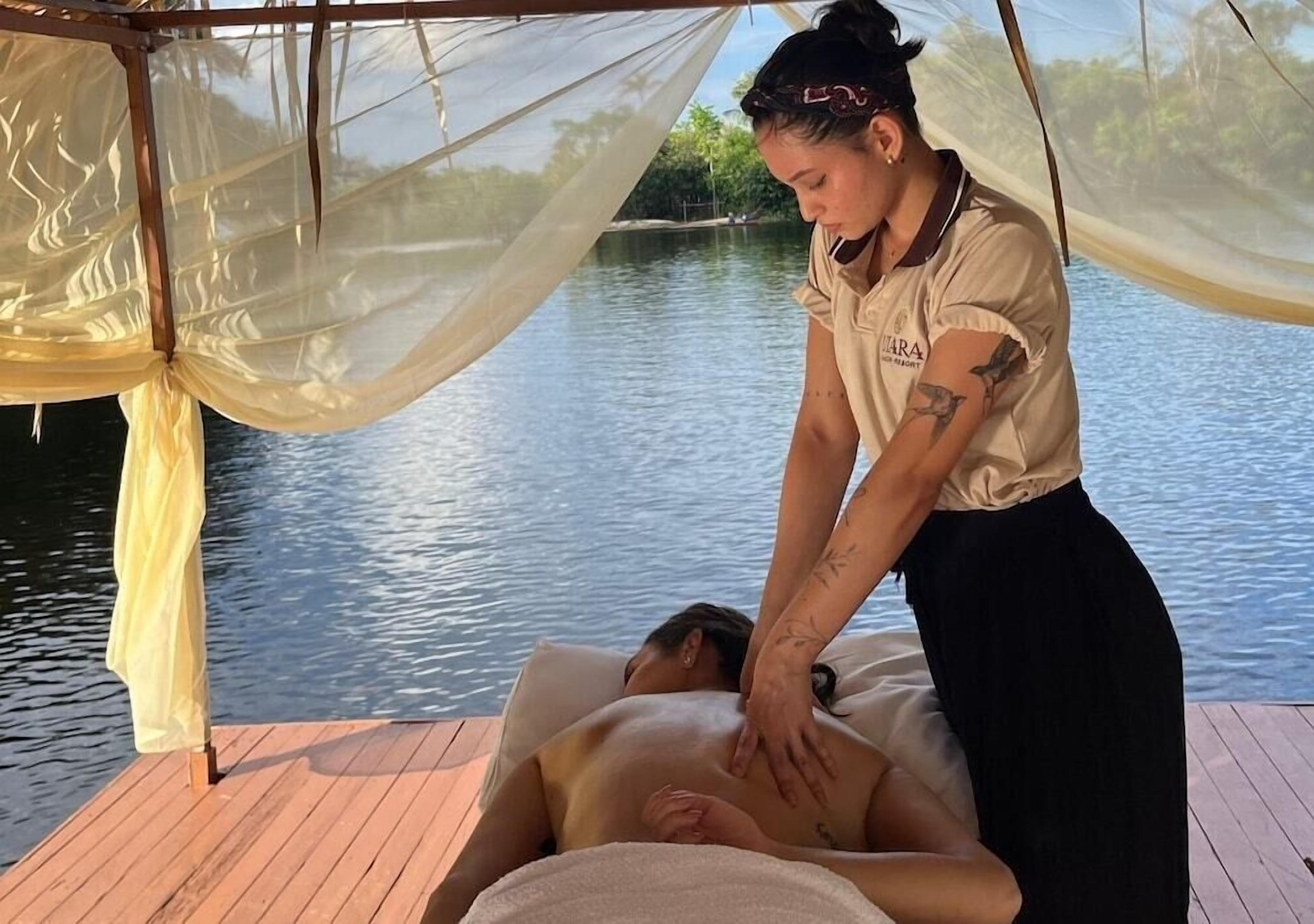 Sessão de massagem em um deck de madeira à beira da água.