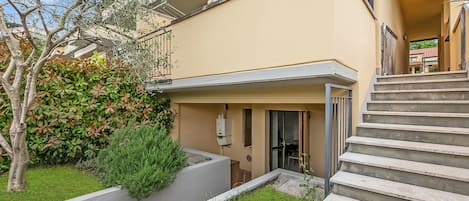Un edificio moderno con techo plano, balcón y una escalera que lleva a la entrada.