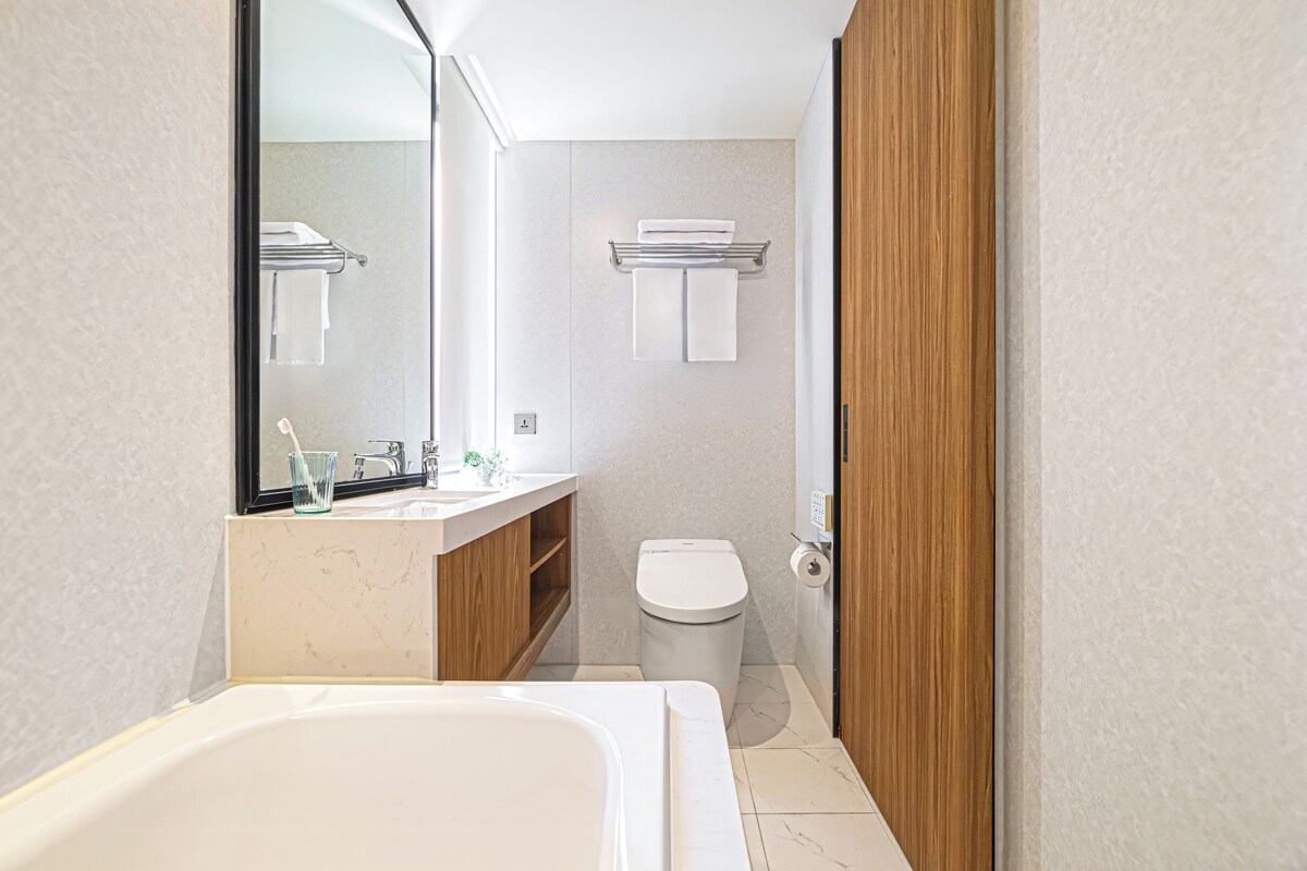 A bathroom with a bathtub, a toilet, a sink, a mirror, and a towel rack.