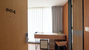A hotel room with a wooden desk, a chair, a small refrigerator, and a window with curtains. - Just Sleep Taipei Zhongshan (Taipei)