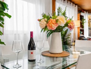 A table with a bottle of wine, two glasses, and a vase with flowers.