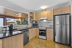 A modern kitchen with wooden cabinets, stainless steel appliances, and a herringbone-patterned floor.