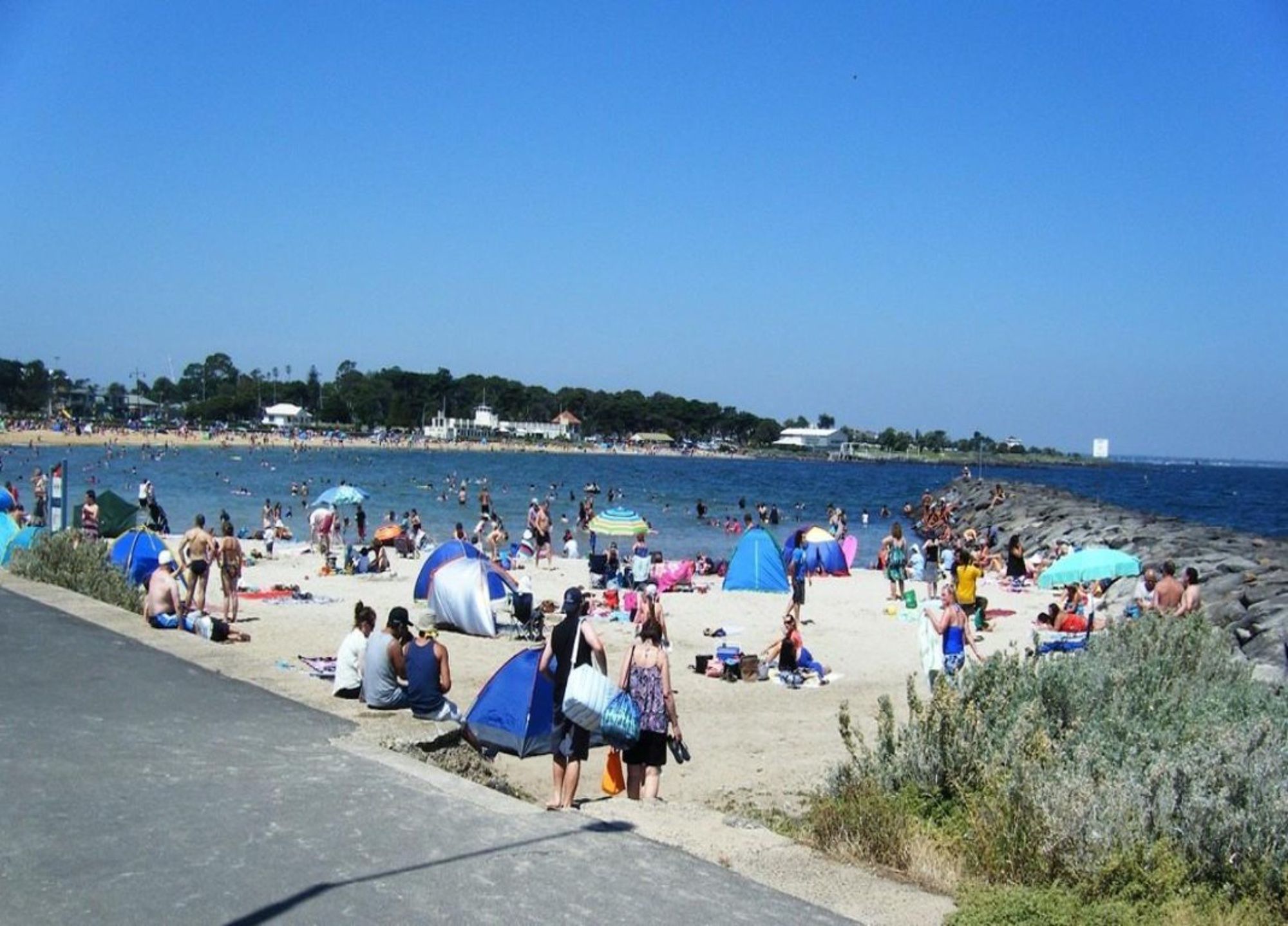 A beach with people, tents, and a clear sky.