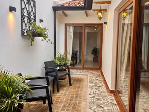 A patio with a table and chairs, potted plants, and a patterned floor. - Colonial Courtyard Suite in Centro Histórico + Tranvía Tram (Cuenca)