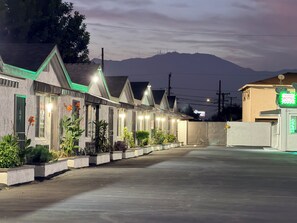 Un motel con diverse camere, un parcheggio e una montagna sullo sfondo.