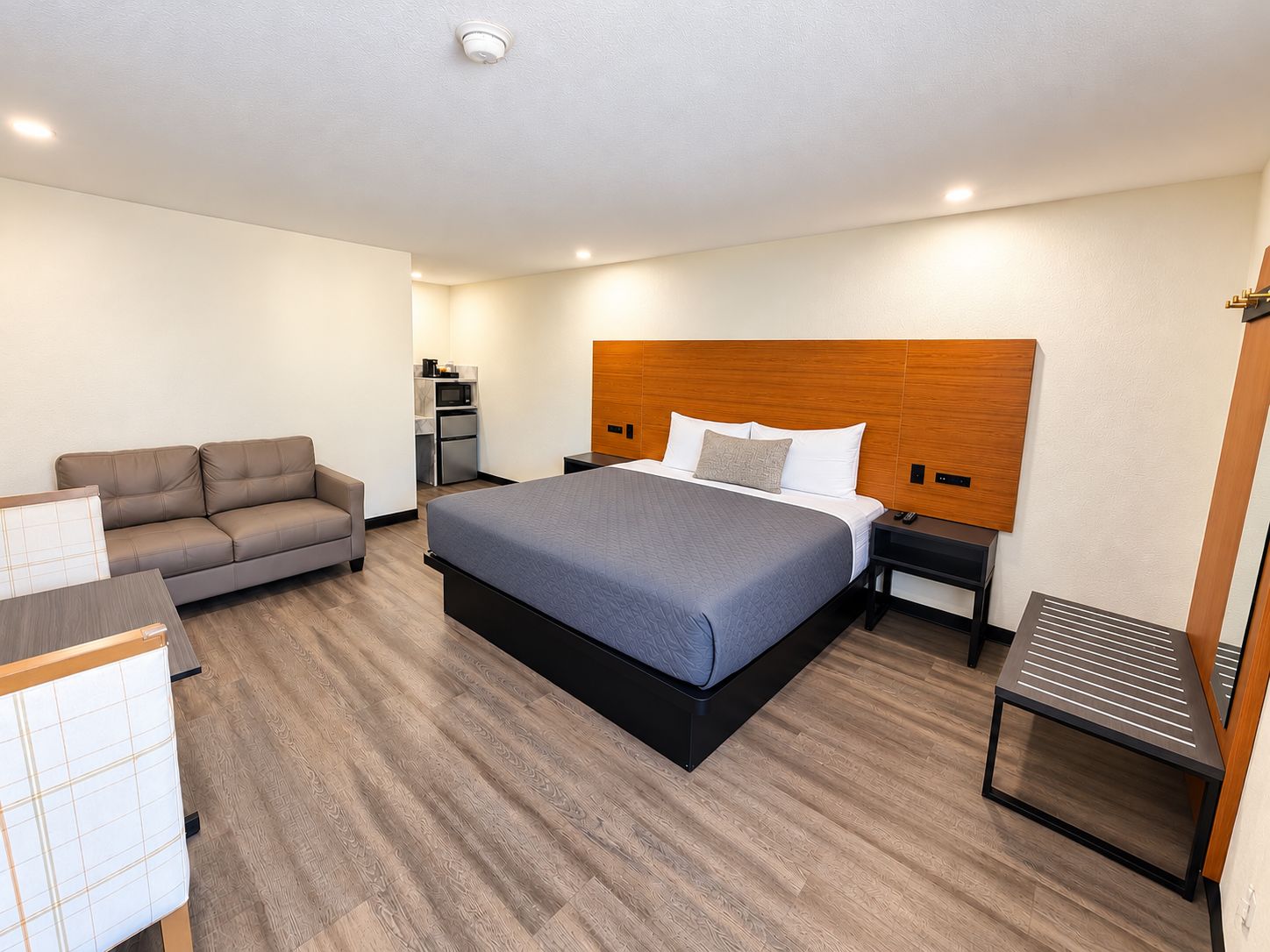 Habitación de hotel con una cama grande, un sofá, un escritorio y una pequeña kitchenette.