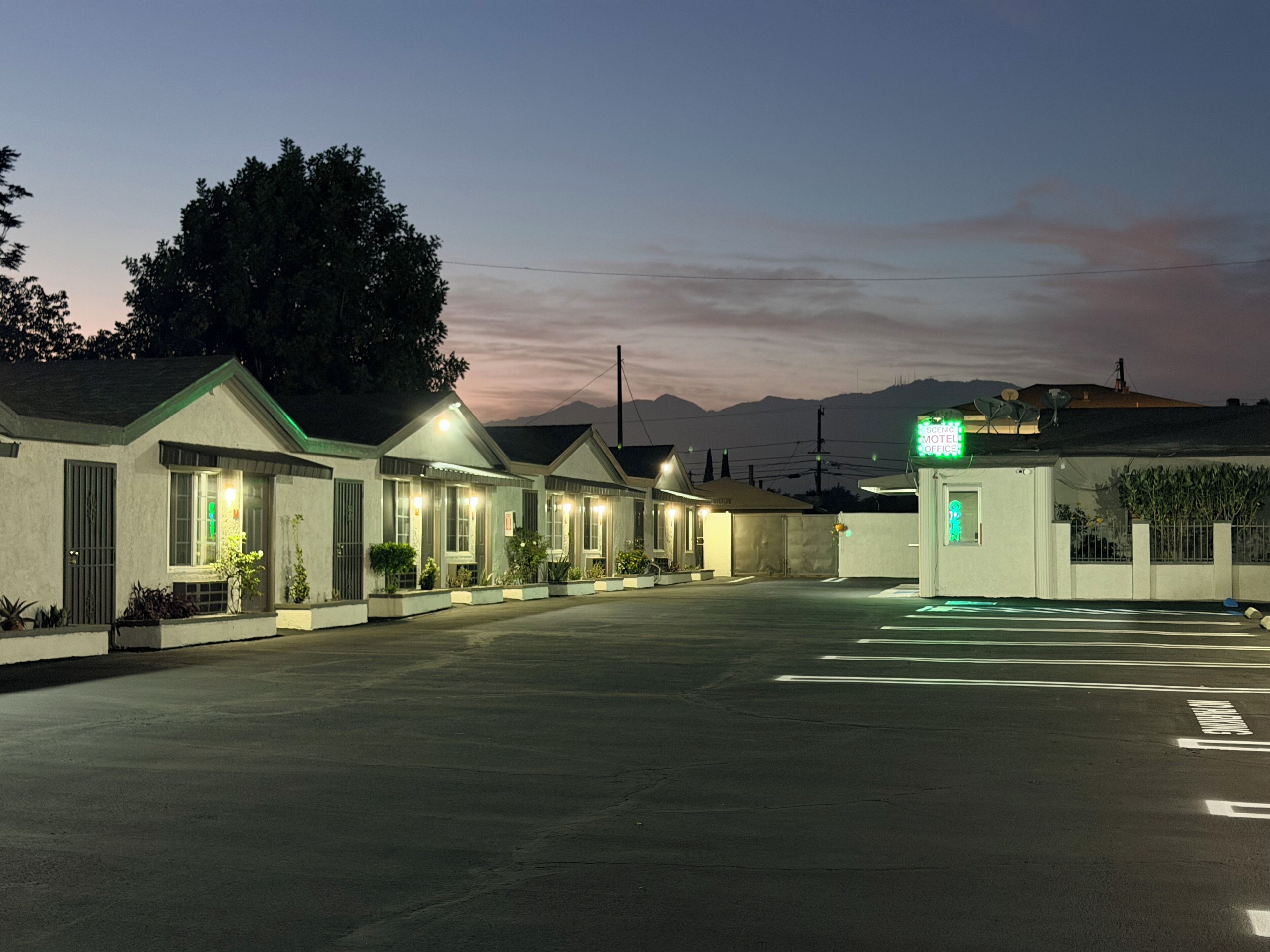 A motel with multiple rooms, a parking lot, and a mountain backdrop.