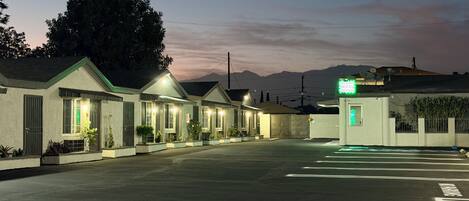 A motel with multiple rooms, a parking lot, and a mountain backdrop.