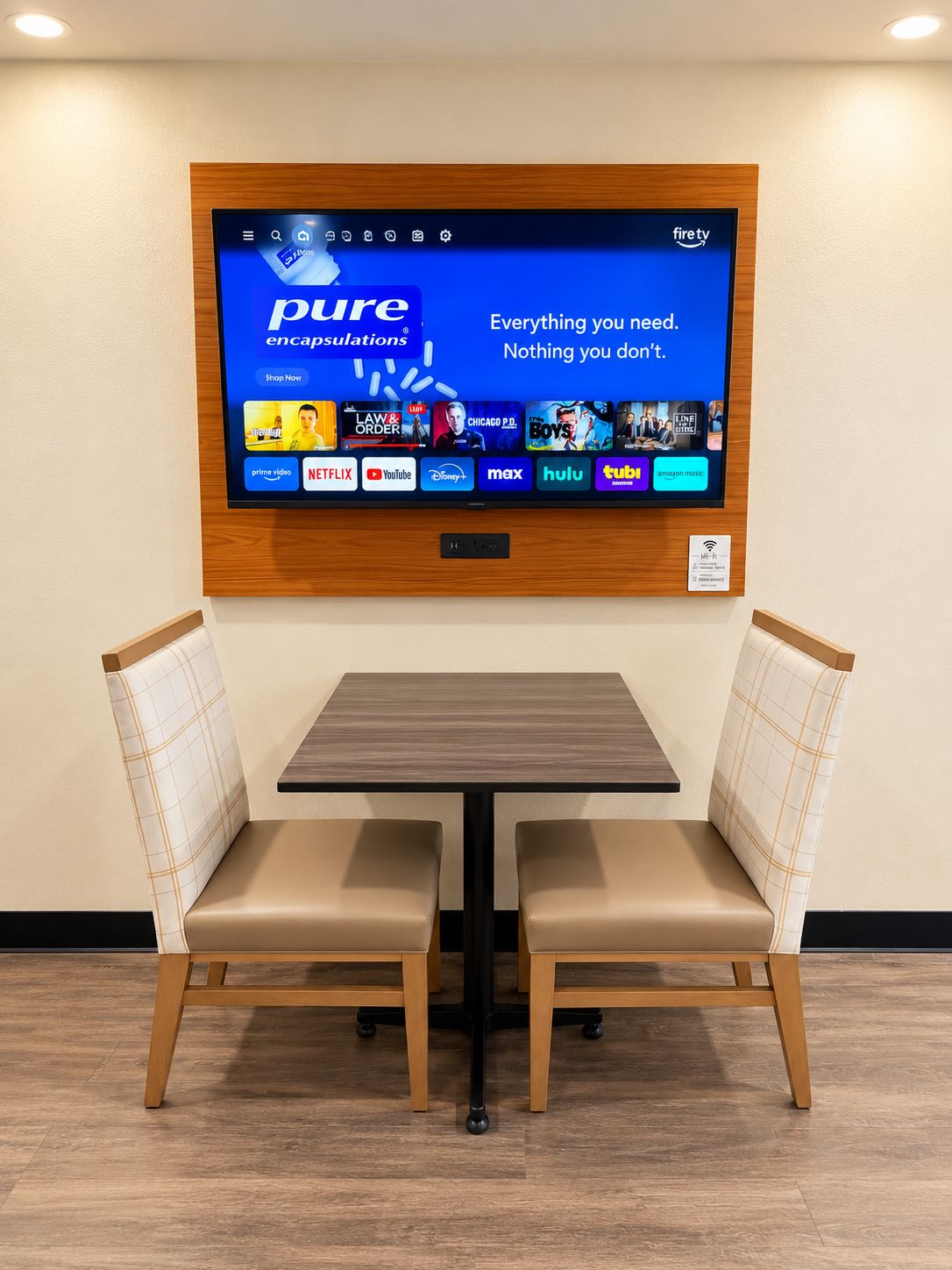 Ett rum med en stor skärm som visar gränssnittet för en streamingtjänst, två stoppade fåtöljer och ett träbord.