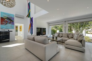 A modern living room with a sectional sofa, a flat-screen TV, and abstract art on the walls. - Villa Amantos - Denia, Costa Blanca (Denia)