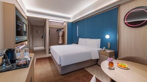 A hotel room with a bed, bedside table, TV, and a small dining area with a fruit plate. - Crystal Orange Shenzhen Bao'an Joy City (Shenzhen)