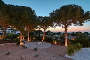 Ein angelegter Garten mit Bäumen, einer Terrassenanlage und Blick auf eine Stadt im Hintergrund.