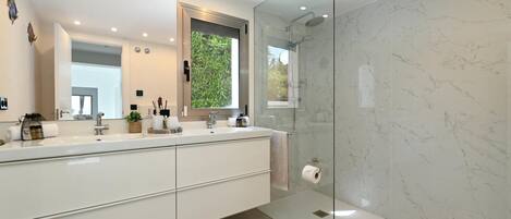 A modern bathroom with a large mirror, a glass shower enclosure, and a white sink.