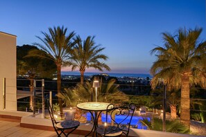 A terrace with a pool, palm trees, and a city view at dusk. - Villa Amantos 10 pax - Denia, Costa Blanca (Denia)