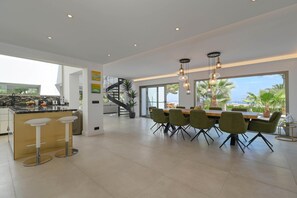 Eine moderne Küche mit Barbereich, einem Essbereich mit Stühlen und einer Treppe zu einer oberen Ebene.