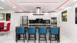 A modern kitchen with white cabinets, stainless steel appliances, and a central island with bar stools.