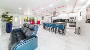 A modern kitchen with white cabinets, a stainless steel range hood, and a central island with bar stools.