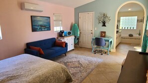 Un dormitorio con cama, sofá azul, escritorio y una pequeña kitchenette.