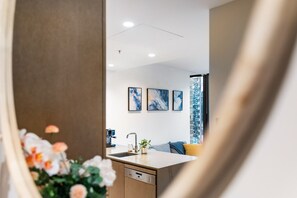 Eine moderne Küche mit Geschirrspüler, Spüle und Arbeitsplatte. An der Wand hängen drei gerahmte Kunstwerke.