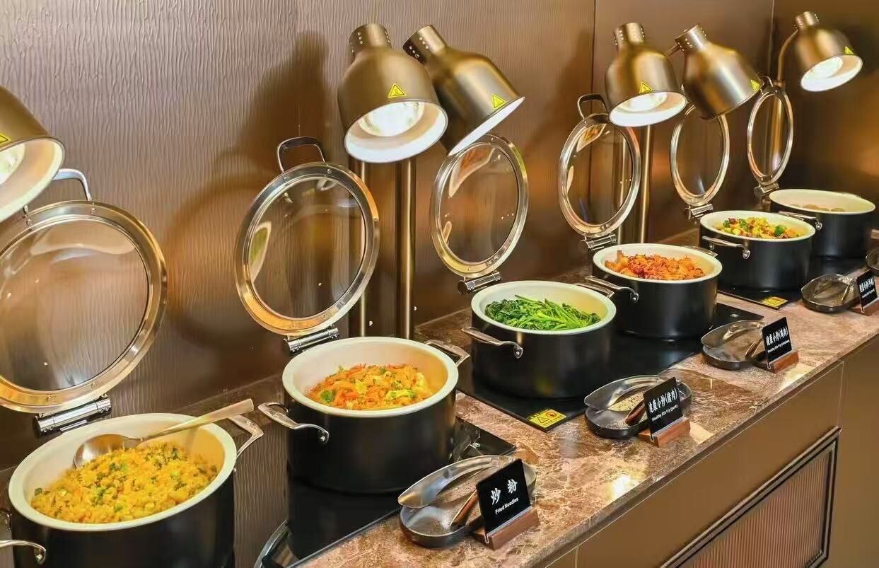 A buffet with various dishes, each in a separate pot with a lid, and a sign indicating the type of cuisine.