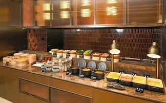 A buffet counter with various food items and containers, a sink, and a mirror.