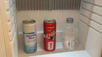 Un refrigerador con tres artículos: una lata de agua Aquafina, una lata de refresco Fifa y una botella de plástico transparente.