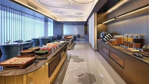 A modern hotel lobby with a long reception desk, a buffet area, and a seating area with blue chairs. - Crystal Orange Hotel Shenzhen Futian (Shenzhen)