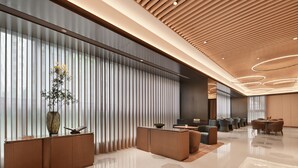 A modern hotel lobby with a reception desk, seating area, and a large window with vertical blinds. - Crystal Orange Hotel Shenzhen Futian (Shenzhen)