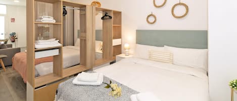 Quarto de hotel moderno com cama, guarda-roupa, mesa de cabeceira e espelho.