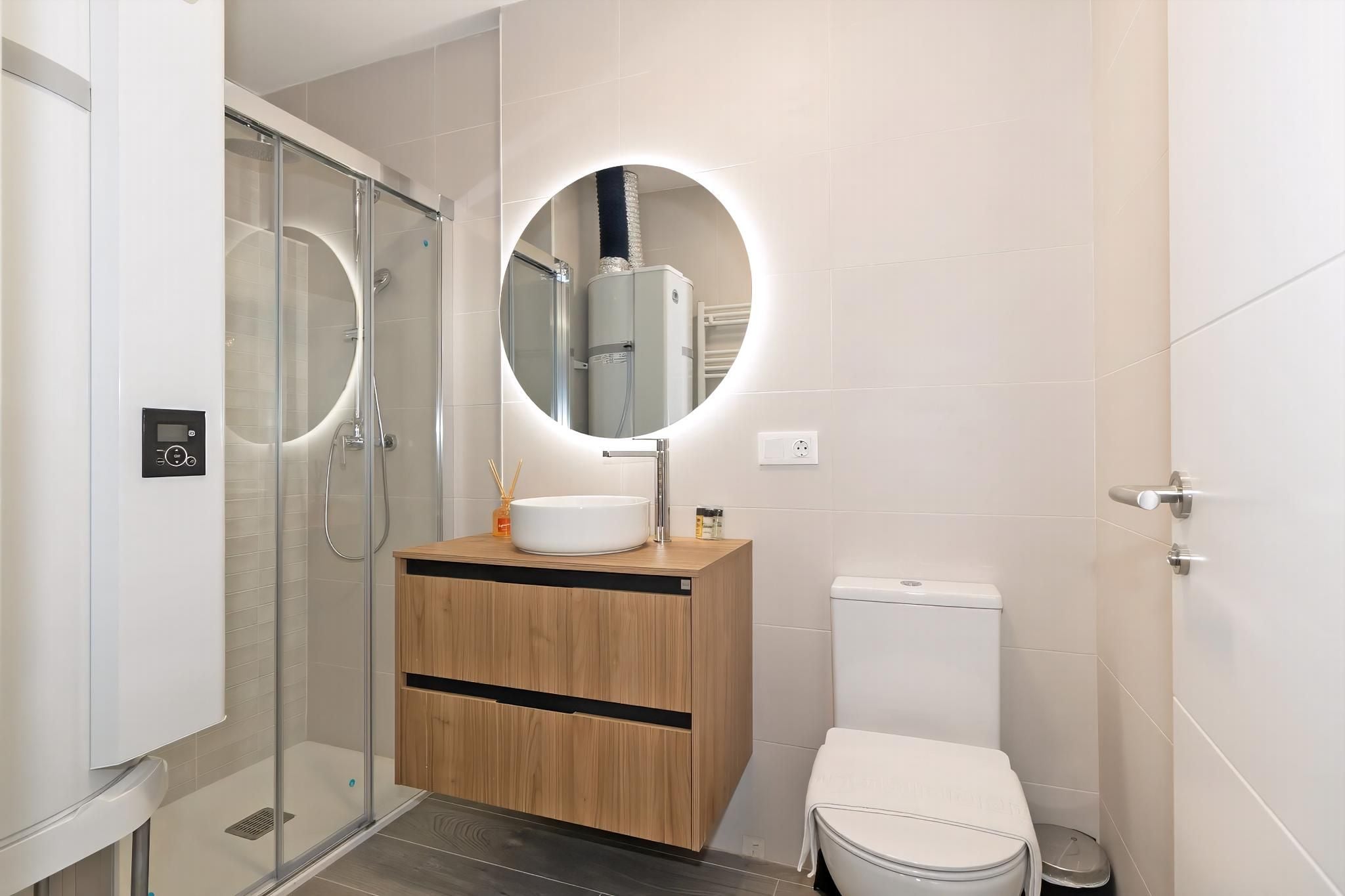 A modern bathroom with a glass-enclosed shower, a wooden vanity with a sink, and a toilet.