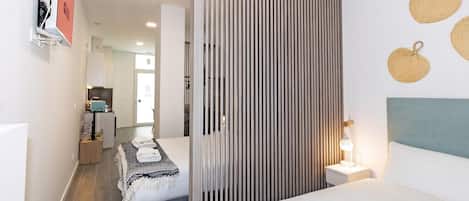 A modern hotel room with a bed, bedside table, and a partition wall.