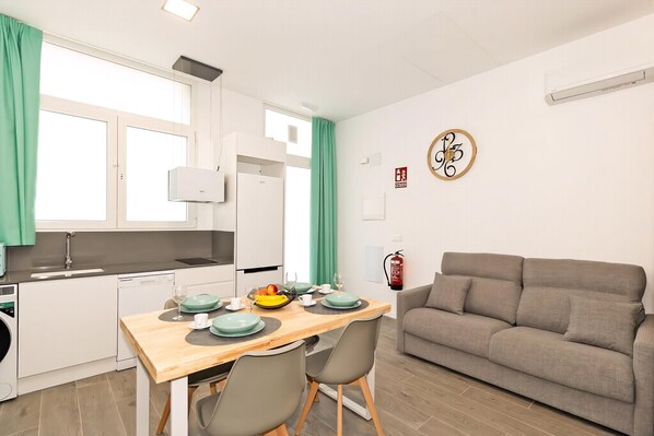 Un espacio habitable pequeño con kitchenette, comedor y sofá.