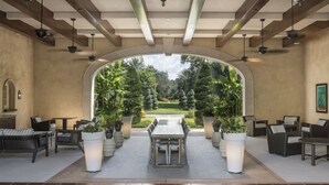 Ein Innenhof mit Blick auf einen gepflegten Garten, ausgestattet mit einem zentralen Tisch und Sitzgelegenheiten.