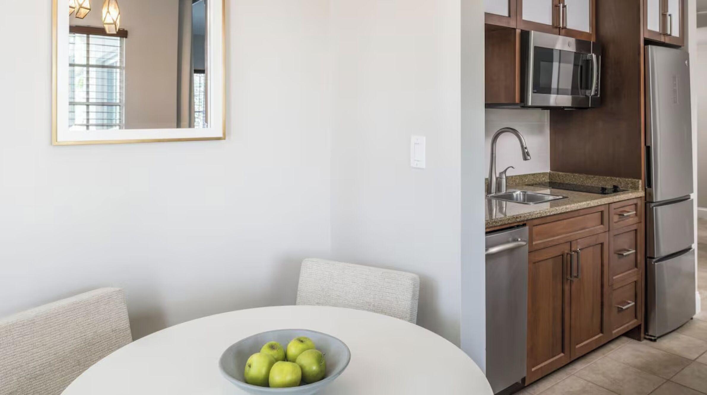A modern kitchen with a microwave, refrigerator, and stainless steel sink.