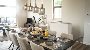 En matplats med ett mörkt träbord, beige stolar och hängande taklampor.