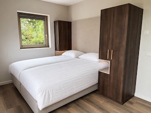 Un dormitorio con cama, ventana y armarios de madera.