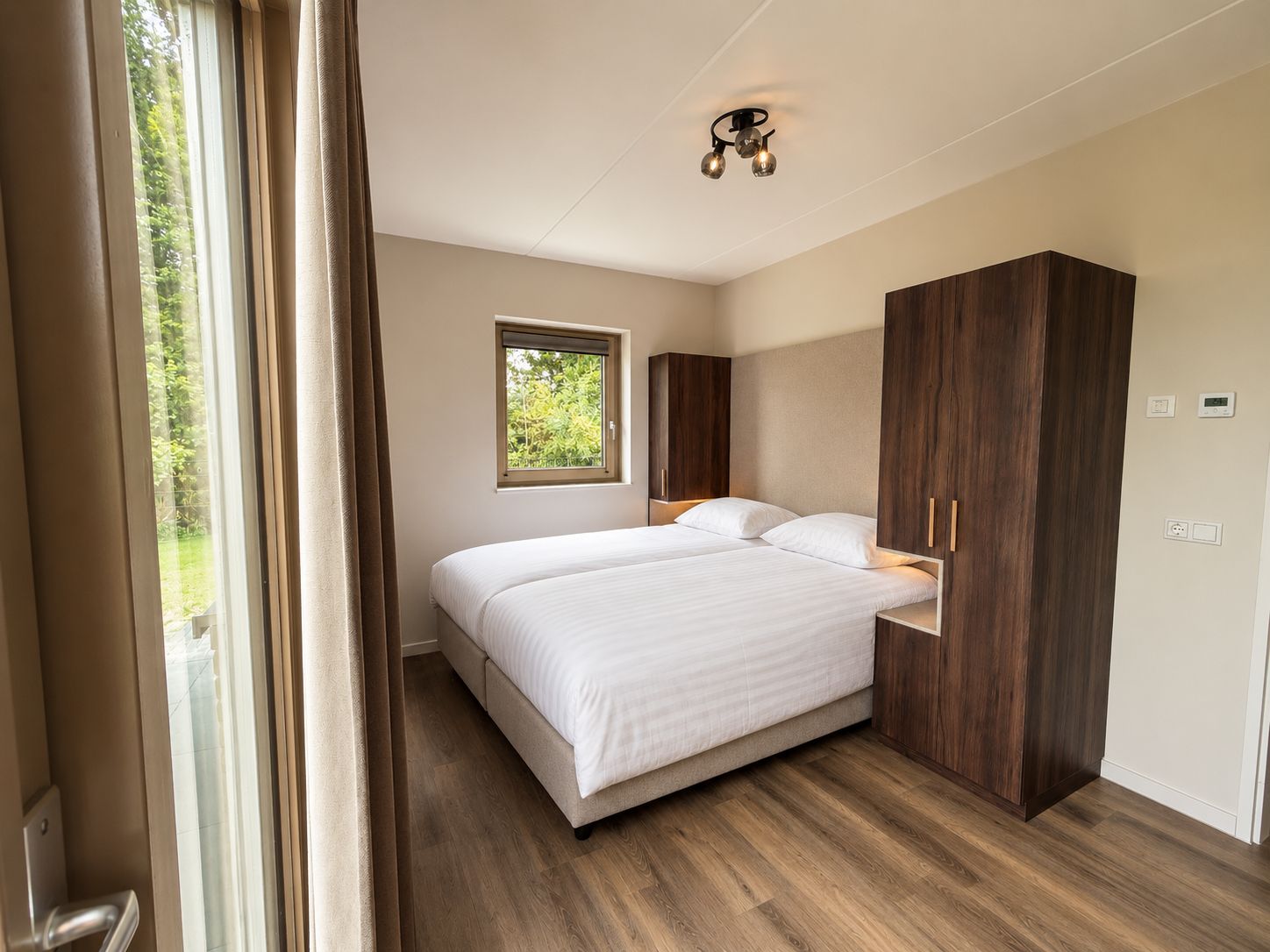 Une chambre à coucher comprenant un lit, une armoire, une fenêtre et un luminaire au plafond.