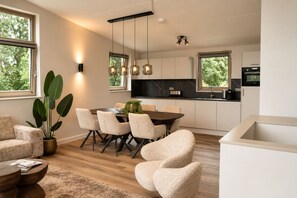 Et moderne køkken med spiseplads, store vinduer og en potteplante.