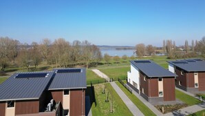 Une rangée de bâtiments modernes dotés de panneaux solaires, une vue dégagée sur un lac et un chemin menant aux bâtiments.