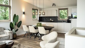 Une cuisine moderne avec un coin repas, de grandes fenêtres et une plante en pot.
