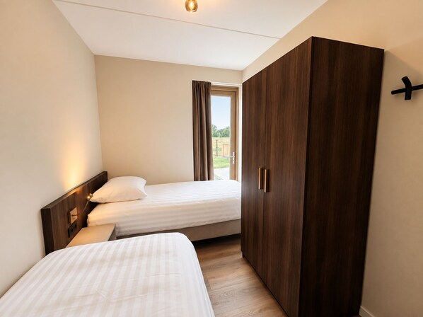 Un dormitorio con dos camas, un armario y una ventana con cortinas.