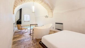 Un dormitorio con una cama grande, una bañera y una silla.